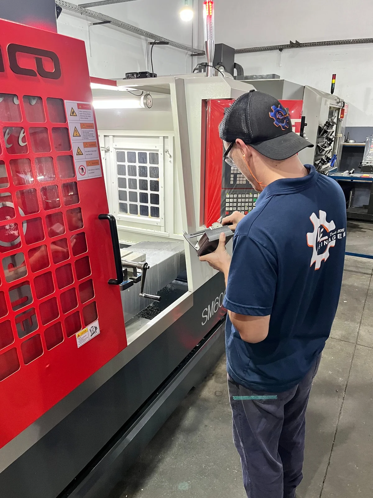 Colaborador da LE Usinagem medindo peça usinada com paquímetro em centro de usinagem CNC